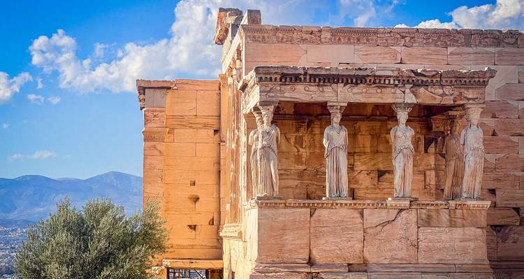 El Pórtico de las Cariátides del Erecteión en la Acrópolis, bañado en la cálida luz de la tarde contra un cielo azul.
