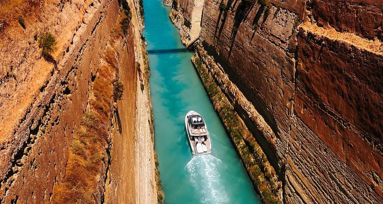 Un barco navegando a través de las aguas azul vívido del estrecho Canal de Corinto de paredes empinadas.