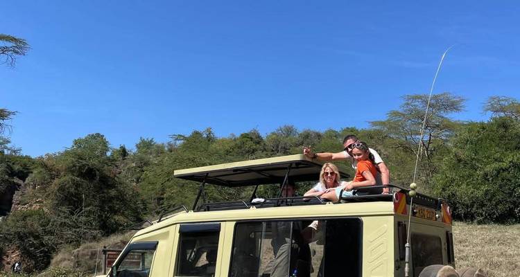 Trois personnes profitant d'un safari, se penchant par le toit d'un véhicule.