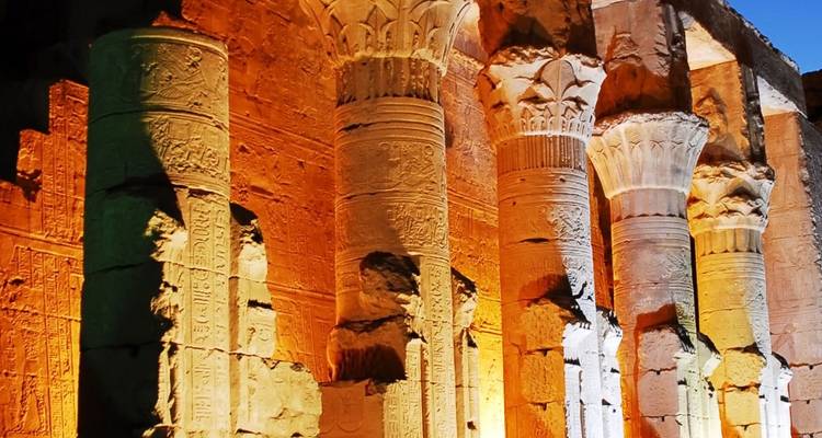 Colonnes illuminées d'un temple égyptien la nuit.