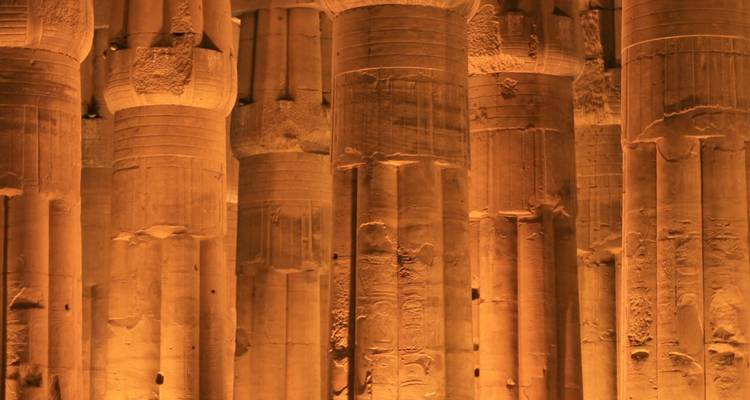 D'énormes colonnes de pierre illuminées la nuit à Louxor.