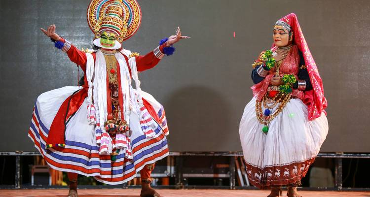 Traditionelle Tänzer in leuchtenden Kostümen, die auf der Bühne auftreten.