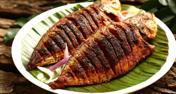 Gericht aus gegrilltem Fisch auf einem Banenenblatt mit Gewürzen.