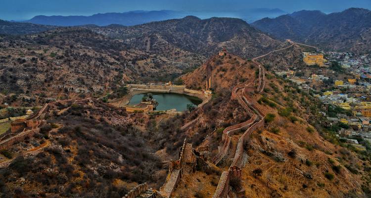 An aerial view of a fort with surrounding hills and a water body.