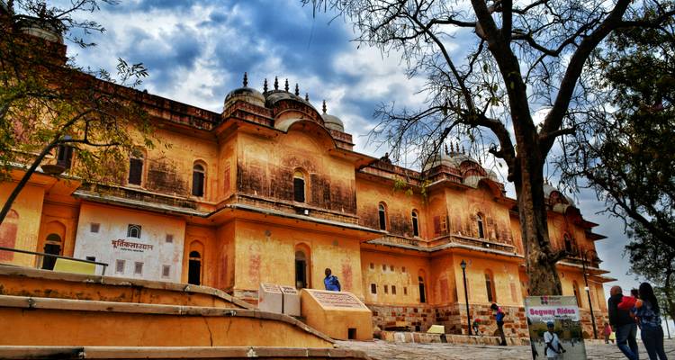 A historic building with yellow walls and people around.