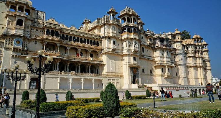 A grand palace with tourists in the garden.