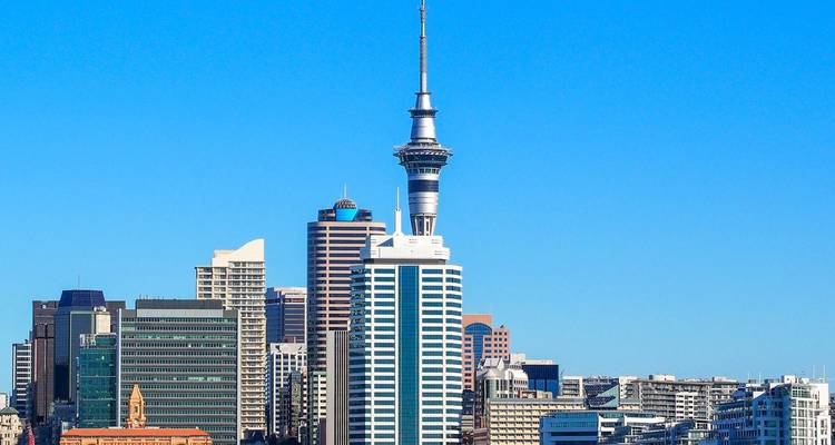 Moderno skyline de Auckland con la Sky Tower bajo un cielo azul vibrante.