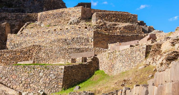 Stone terraces and walls of Ollantaytambo archaeological site under bright blue sky.
