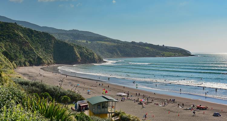 Strandszene mit Menschen, die das Meer und die Wellen genießen.
