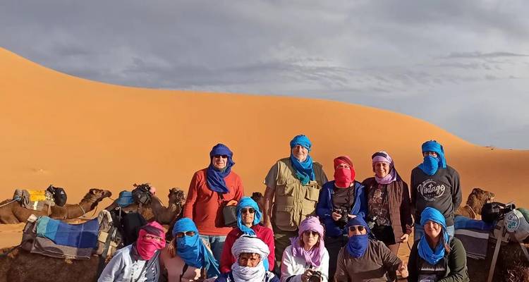 Photo de groupe de personnes dans un décor désertique avec des chameaux.