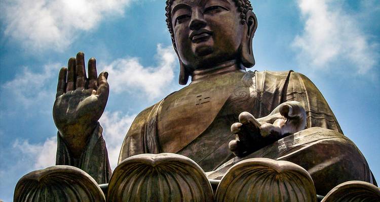 Giant Buddha against a blue sky with clouds.