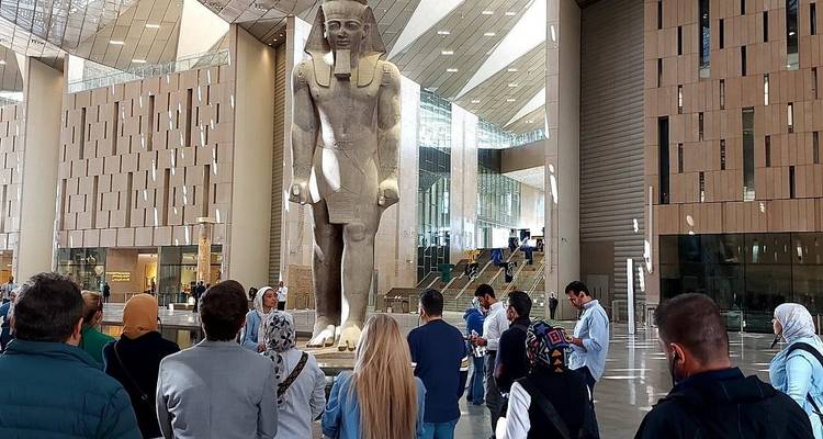 Group of tourists inside a modern museum, gathered around a large statue.