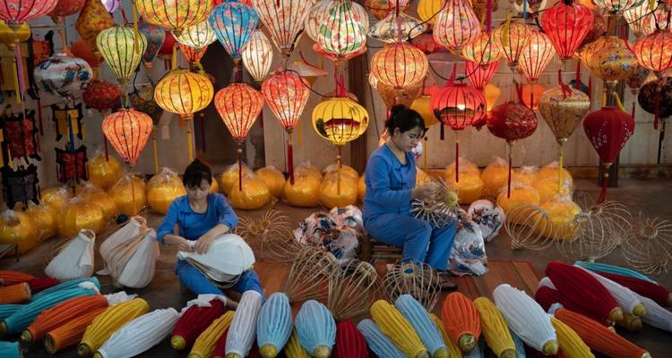 Des gens créent des lanternes traditionnelles dans une boutique colorée.