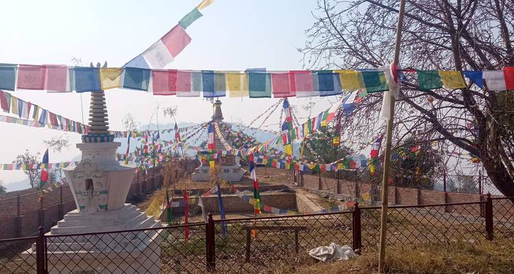 Prayer flags decorating a stupa overlooking a valley.