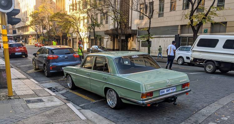 Street view with parked cars and buildings in a city environment.