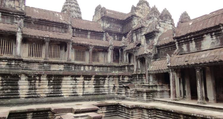 Cour intérieure d'Angkor Vat avec des colonnes de pierre érodées, assombries par l'âge et la mousse.