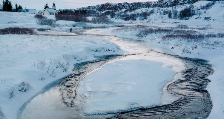 Un río congelado serpenteando a través de un paisaje nevado con árboles.