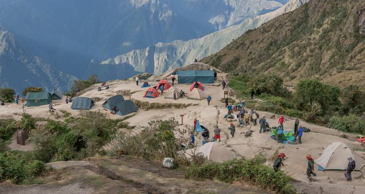 Campamento en el Sendero del Inca con excursionistas armando carpas en la cima de una cresta andina alta.
