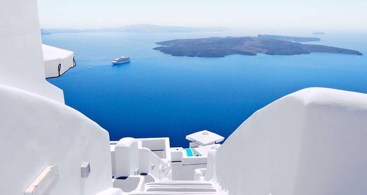 Witte architectuur met uitzicht op zee in Santorini met een cruiseschip in de verte.