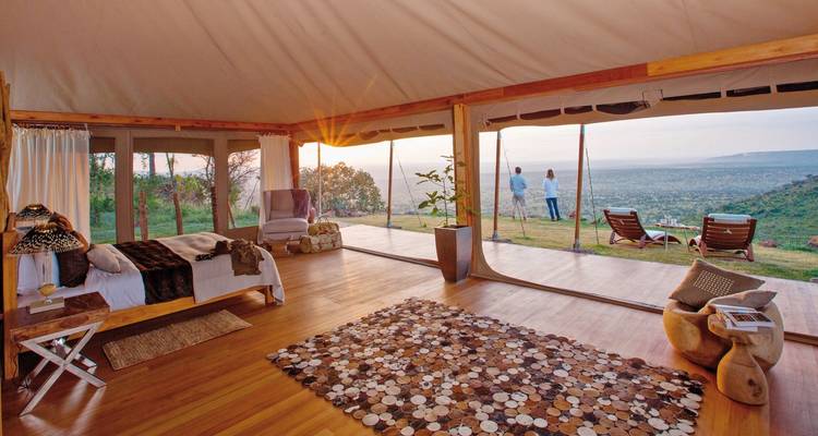 Lodge de tentes luxueux surplombant un vaste paysage.