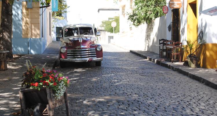 Kopfsteinpflasterstraße mit einem Oldtimer und bunten Gebäuden.