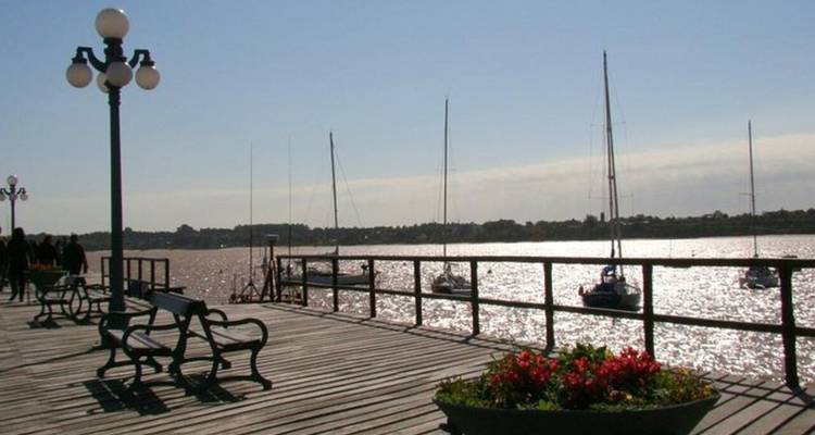 Promenade mit Bänken und Segelbooten im Wasser.