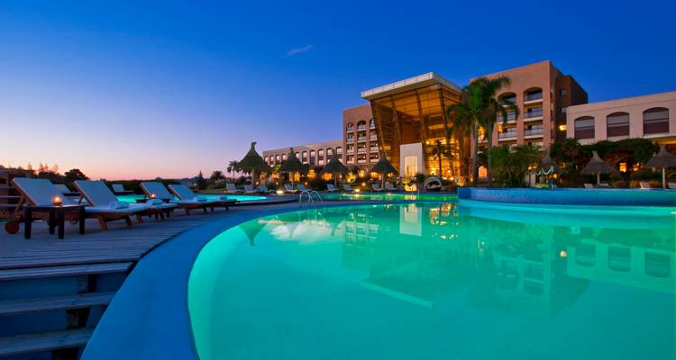 Luxuriöses Resort mit einem großen Swimmingpool, der in der Dämmerung beleuchtet ist.