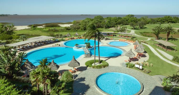 Luftaufnahme eines Resorts mit mehreren Pools und einer malerischen Landschaft.