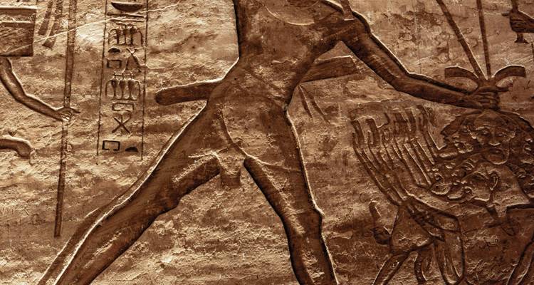 Gedetailleerde beeldhouwwerk van een figuur op een stenen muur.