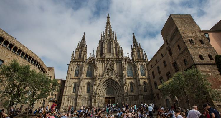 Imposante gevel van de Kathedraal van Barcelona die uittorent boven een levendig plein vol bezoekers.