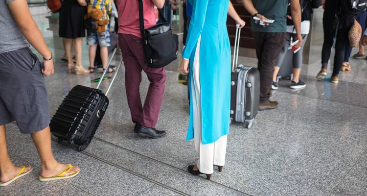 Des voyageurs debout avec leurs bagages dans un aéroport.