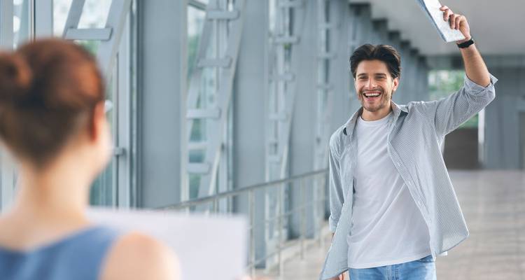 Homme saluant un ami avec un sourire à l'aéroport.