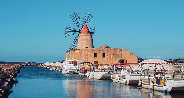Moulin à vent sur un canal avec des bateaux amarrés.
