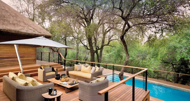 Deck with furniture and a small pool overlooking a forest.