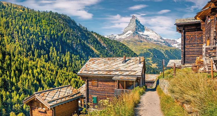 Majestätische Berglandschaft mit Hütten und einem markanten Gipfel.