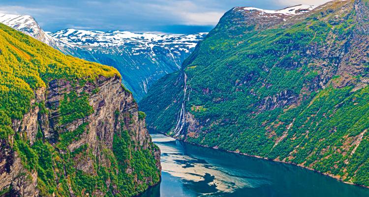 Steile Fjorde mit schneebedeckten Gipfeln und fließenden Wasserfällen.