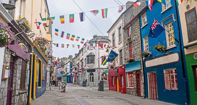 Rue animée avec des drapeaux suspendus et des bâtiments colorés.