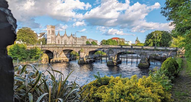 Pont de pierre enjambant une rivière entourée d'une végétation luxuriante.