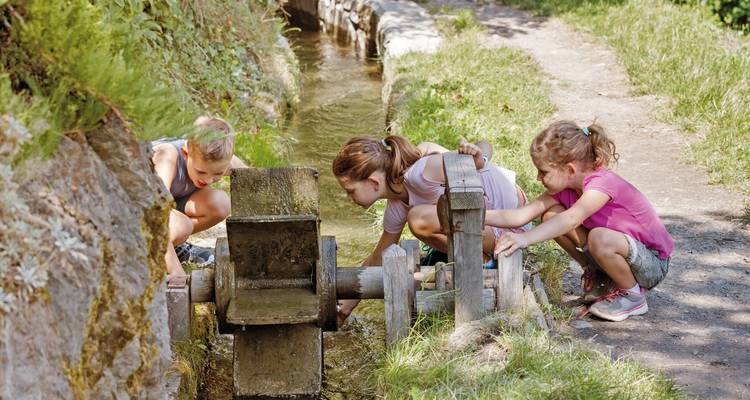 Children playing with a water structure in a natural setting.