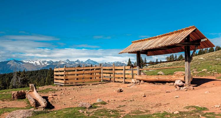 Mountainous landscape with a wooden shelter and clear skies.