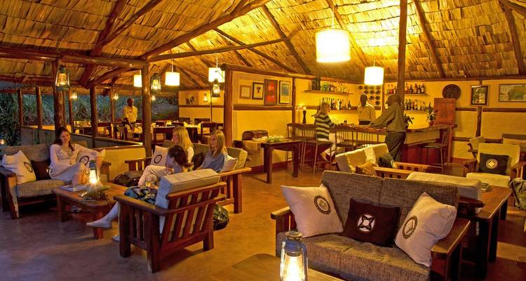 Intérieur d'un lodge confortable avec des gens qui se détendent et un bar en arrière-plan.