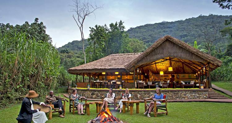 Un groupe de personnes assises autour d'un feu de camp devant un chalet.