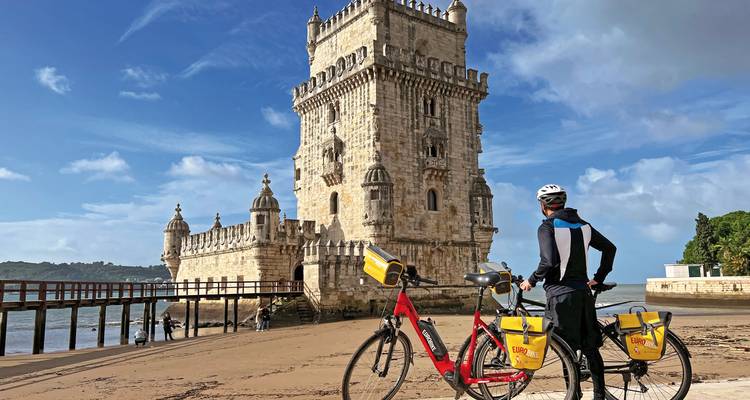 Radfahrer in der Nähe des Belém-Turms an einem Sandstrand.