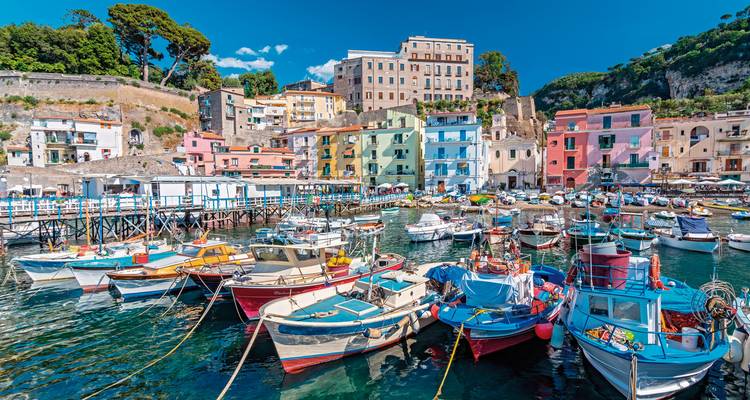 Een levendige vissershaven met kleurrijke boten en pastelkleurige gebouwen langs het water.
