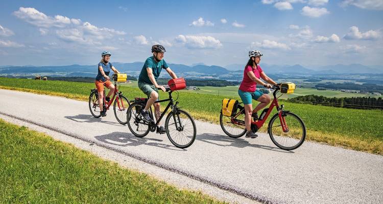 Grupo de ciclistas disfrutando de un camino soleado con vistas a las montañas.