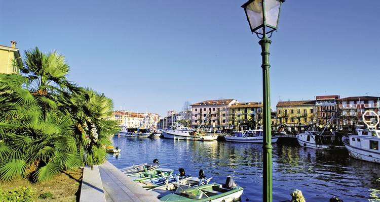 Canal lined with boats and buildings under a clear sky.
