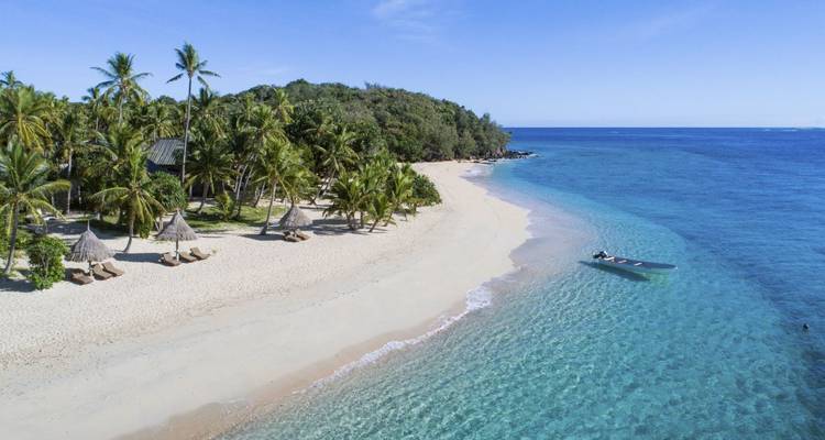 Luftaufnahme eines tropischen Strandes mit einem Boot im Wasser.