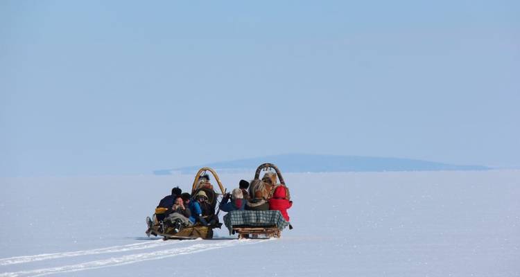 People riding a sled across a frozen landscape.