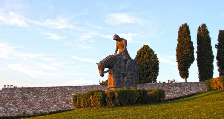 Sculpture d'un cavalier sur un cheval dans un cadre de jardin.