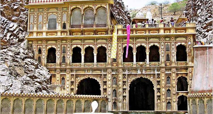 Façade de temple complexe avec des touristes au niveau supérieur.